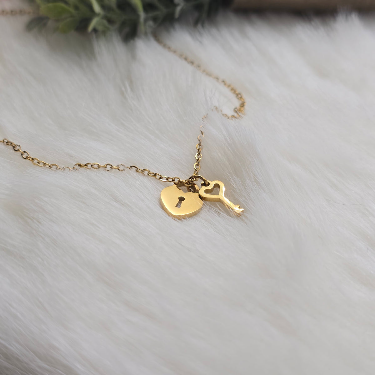 Gold necklace with a heart and key pendant on a white fur background
