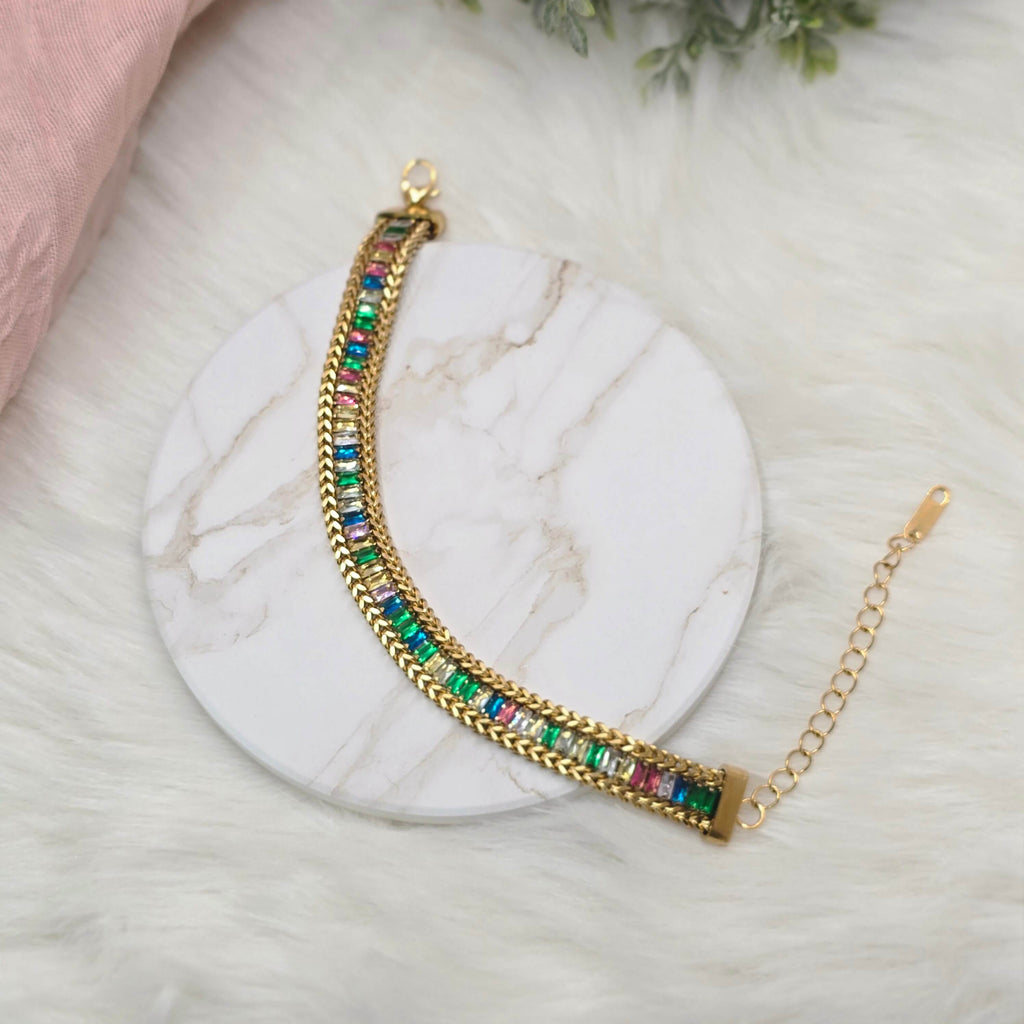 Gold bracelet with colorful beads on a marble surface