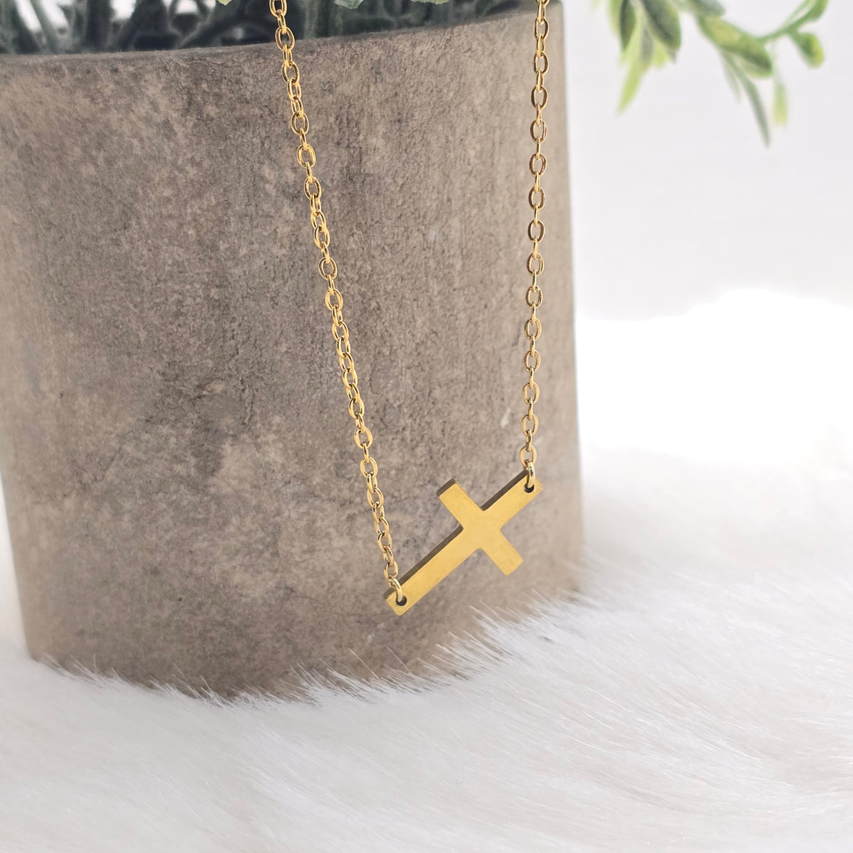 Gold necklace with a cross pendant on a gray surface